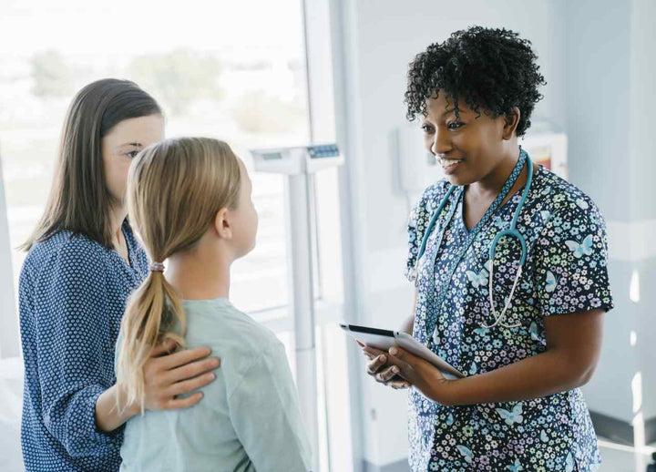 A child sitting with her mother while doctor addresses them both