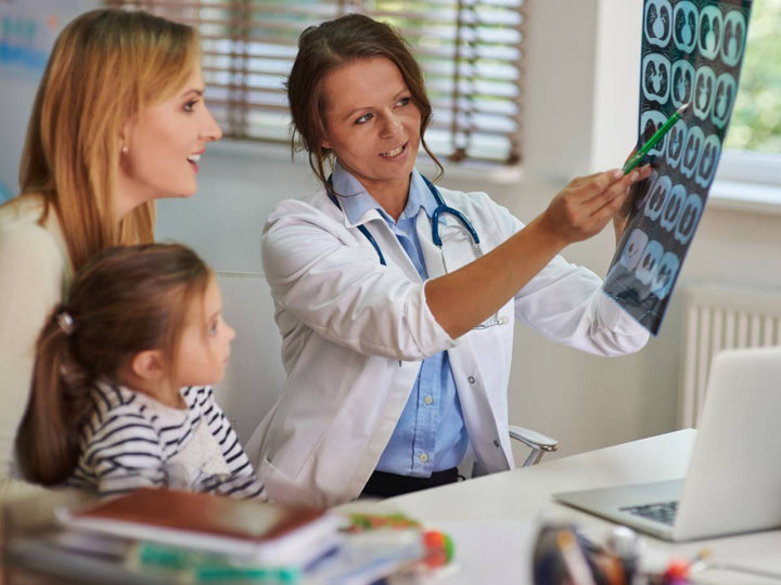 A doctor showing a mom and her daughter an xray and explaining it to them
