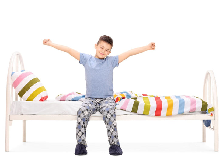 a child sitting and streching on bed