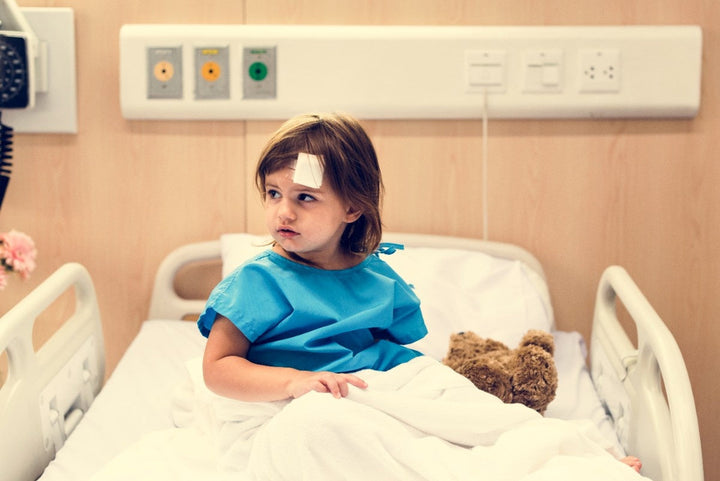 Unhappy young sick girl with teddy in bed